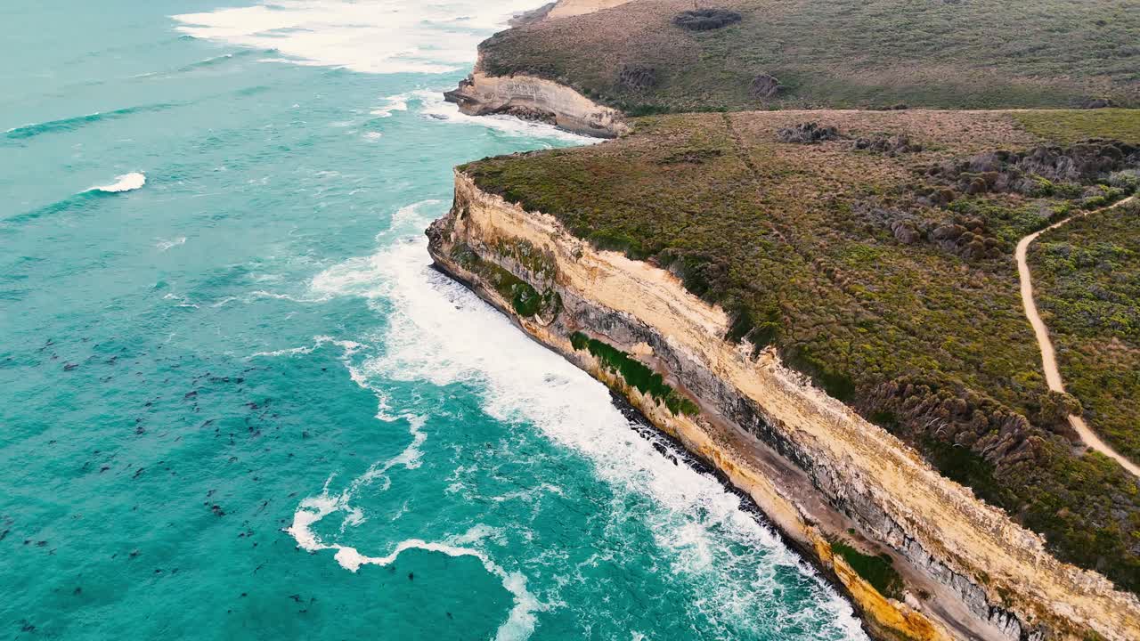Drone footage captures the dramatic cliffs and turquoise waters of Port Campbell, Australia, with sweeping aerial views and natural lighting