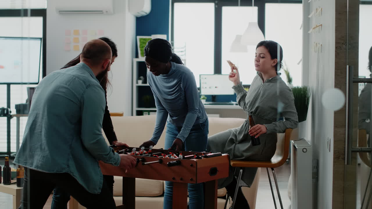 Colleagues playing soccer game at foosball table