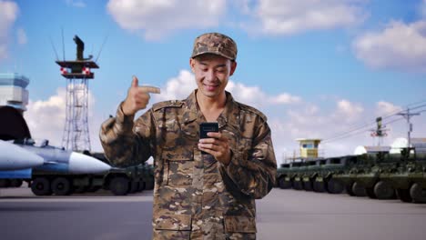 personal militar sonriente usando un teléfono inteligente en una base militar