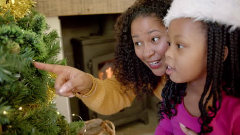 happy african american mother and daughter decorating christmas tree