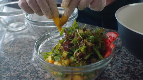 the cook putting more ingredients into the salad bowl