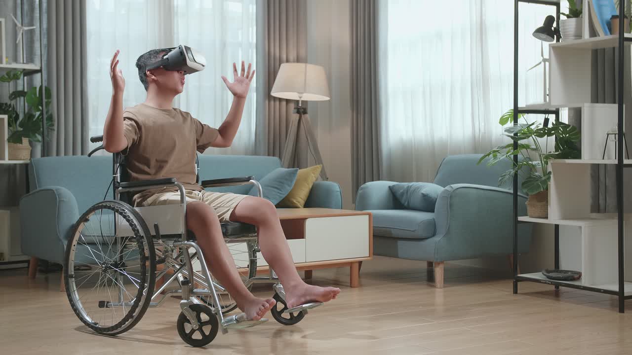 Young Asian Boy Sitting In A Wheelchair While Wearing Virtual Reality Goggles At Home
