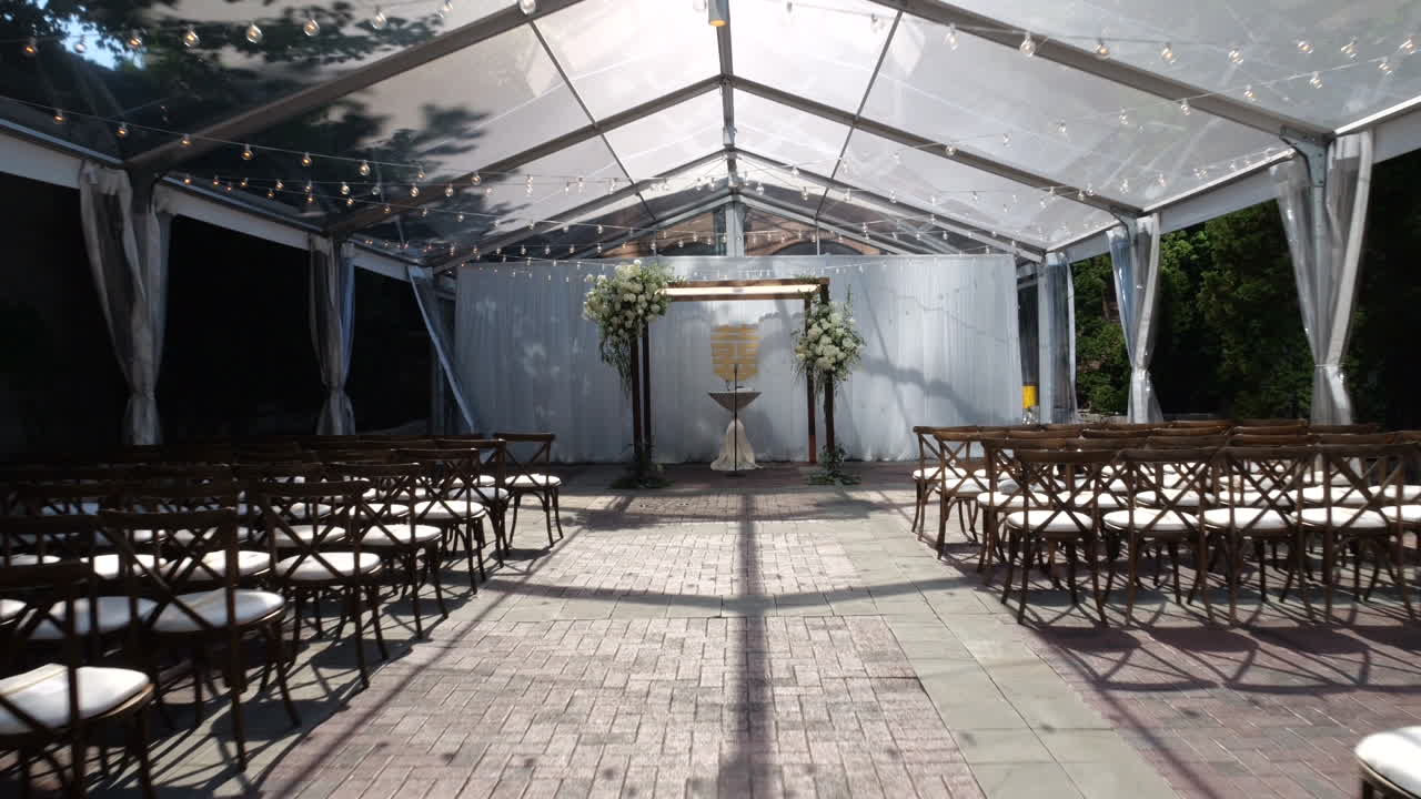 lugar de boda vacío en el jardín de la ciudad, sillas y lugar de ceremonia bajo techo de cristal en un día soleado de verano, tiro dramático que se acerca