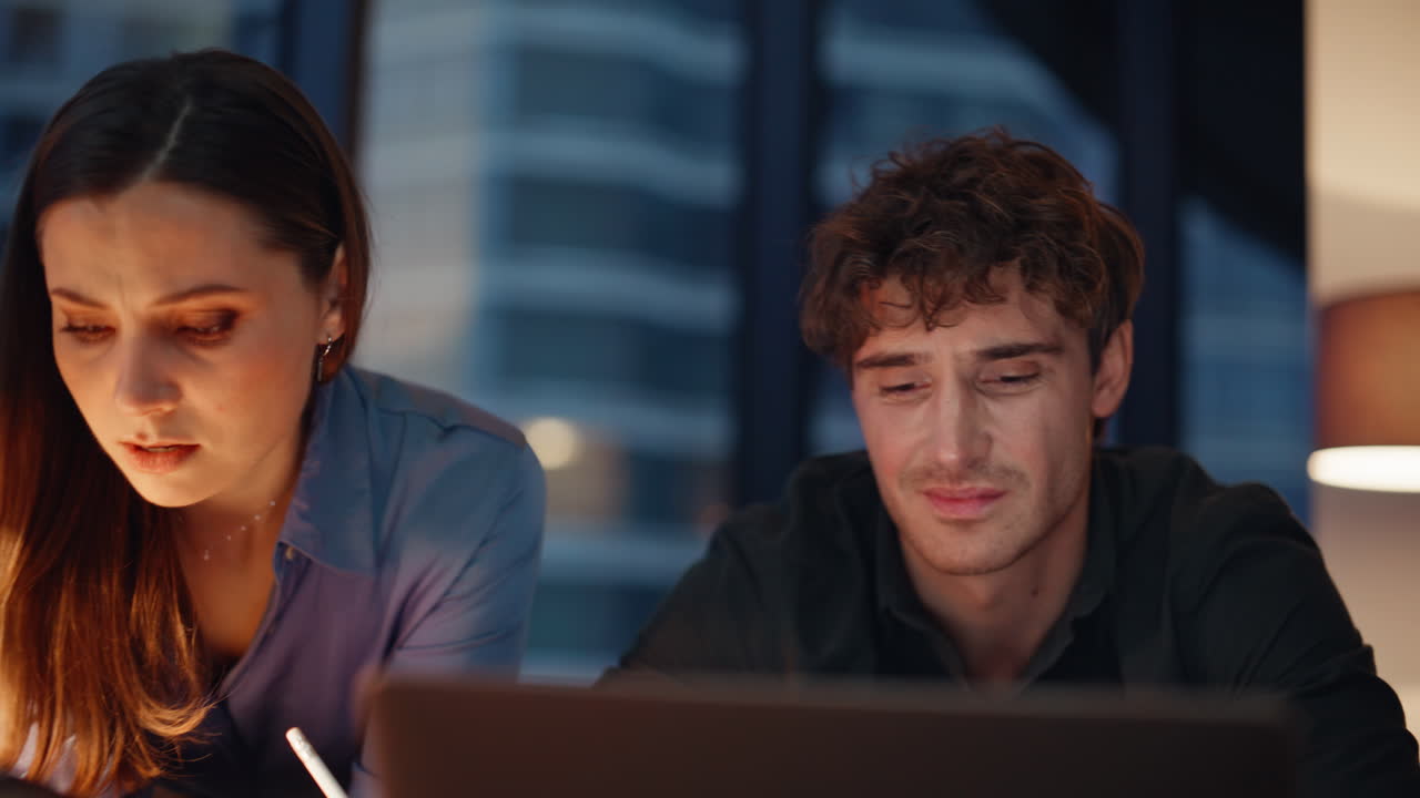 Stressed office team discussing problem looking laptop at dark workplace closeup