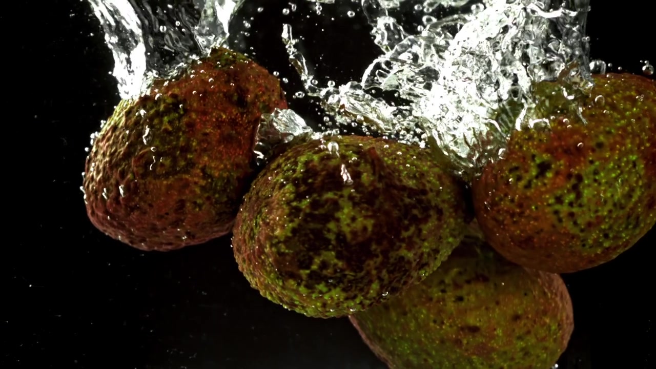 Avocadi freschi che cadono nell'acqua con schizzi e bolle