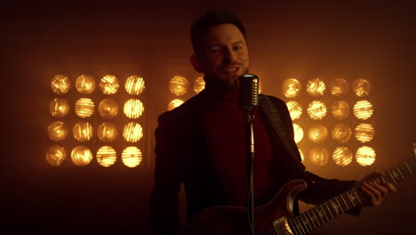 dancing vocalist singing mic in spotlights close up. man musician holding guitar