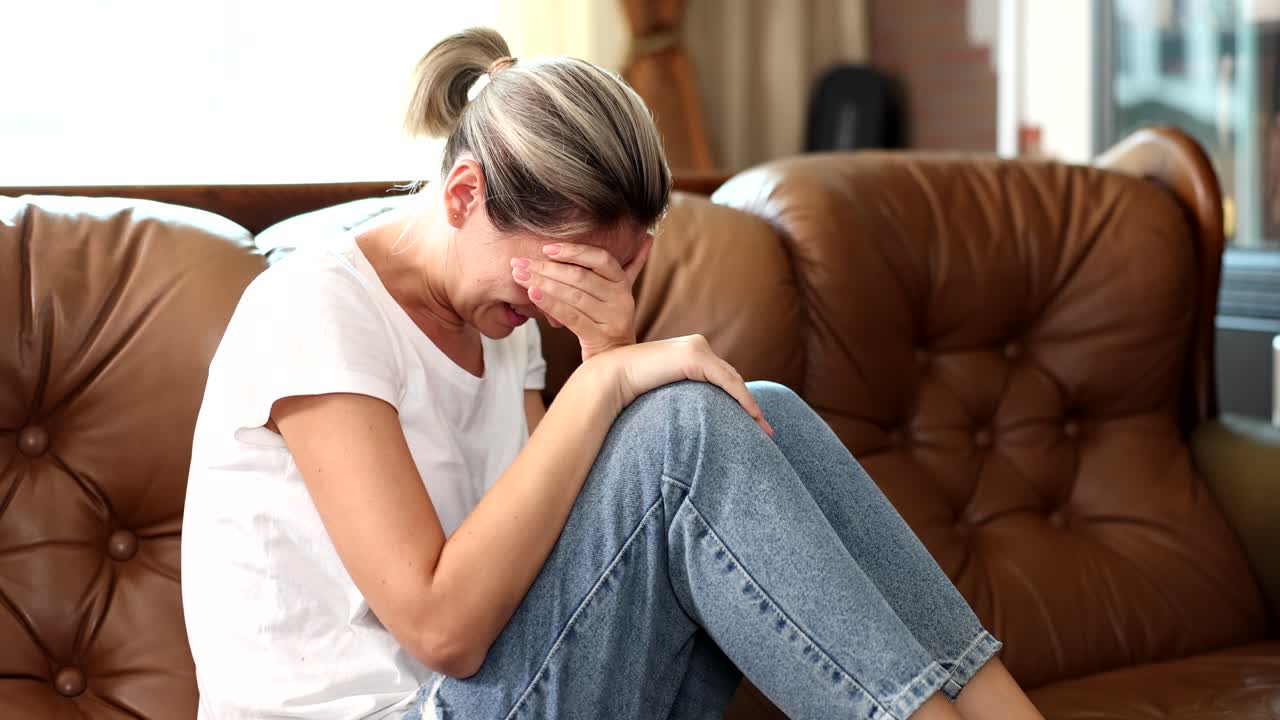 A sad woman crying on the couch