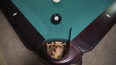 player sinking black 8-ball into corner pocket to win game of billiards