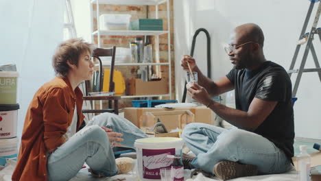 young couple mixing paint colors and discussing home renovation ideas