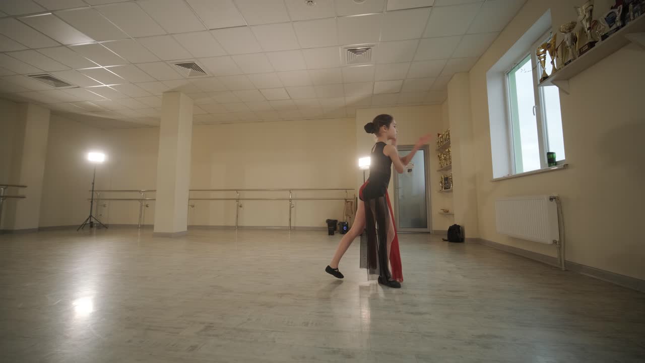 un grupo de jóvenes estudiantes de ballet con ropa de baile negra practicando posiciones en un amplio estudio de ballet con pisos de madera y barras montadas en la pared. expresiones enfocadas y movimientos sincronizados.