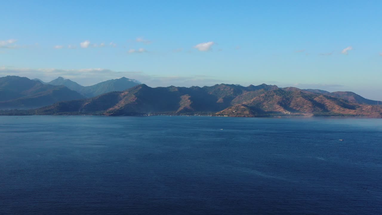 인도네시아의 해안선에서 일출 밝은 하늘에 열대 섬의 산 주변 깊고 푸른 바다의 평화로운 바다