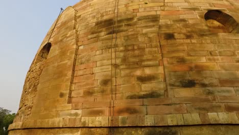 Die-Wunderschöne-Alte-Dhamek-Stupa-In-Sarnath,-Indien,-Mit-Floralen-Schnitzereien-An-Der-Steinwand,-Die-Nach-Unten-Schwenkt