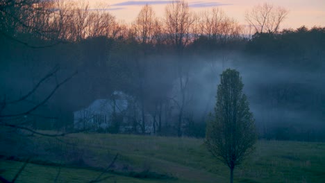 Una-Hermosa-Y-Vívida-Puesta-De-Sol-De-Principios-De-Primavera-En-El-Campo,-Con-Una-Casa-Que-Libera-Humo-En-El-Fondo