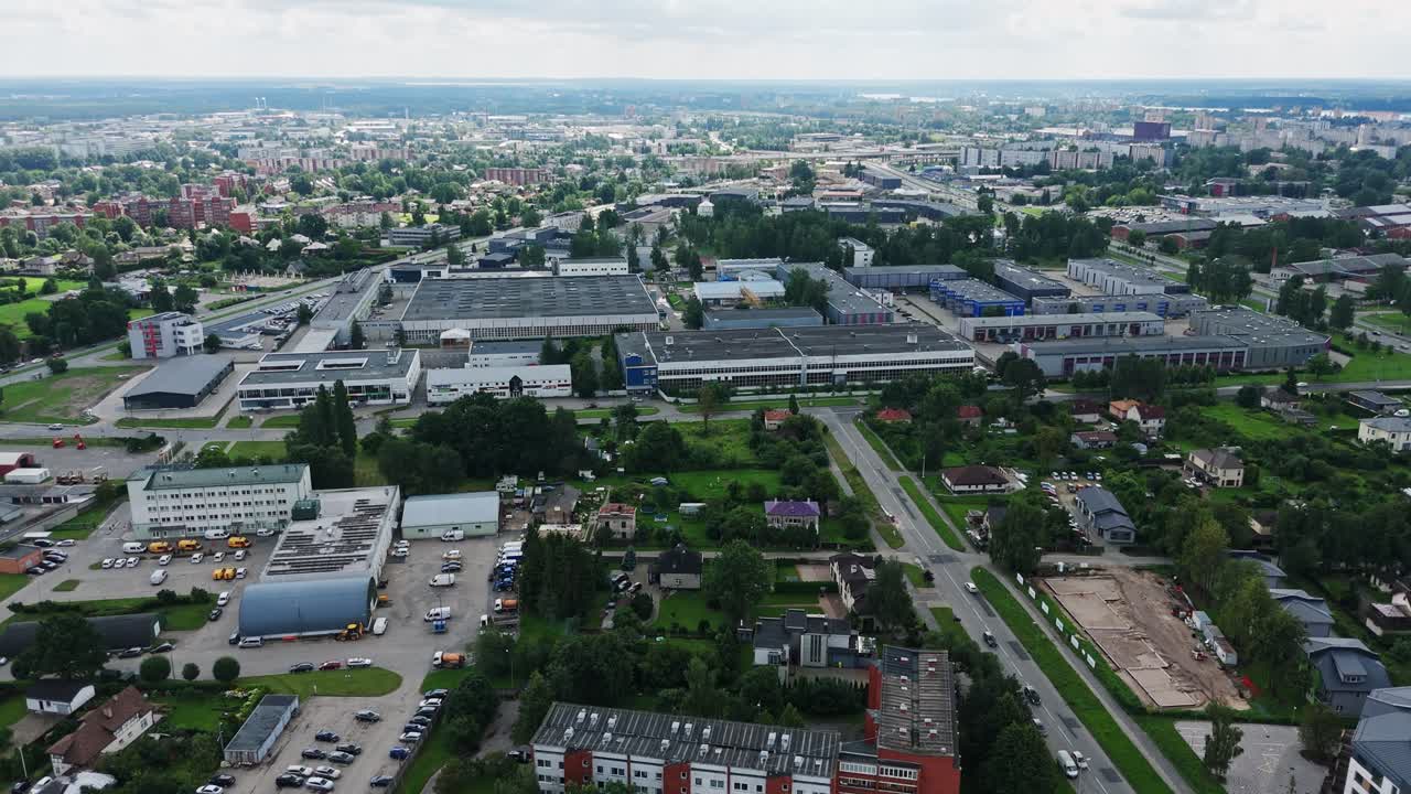 Drone riprende ampie riprese aeree della zona industriale di Darzciems, mostrando fabbriche e magazzini.