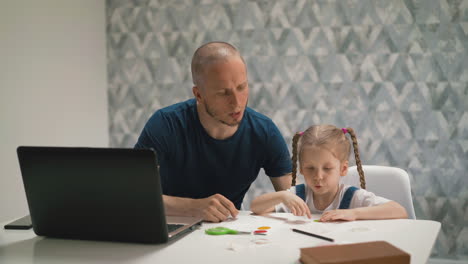 father helps daughter glue colorful sticker on paper