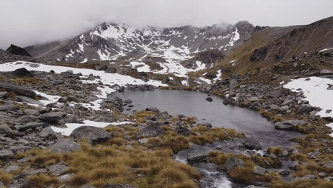 Rocks-And-Snow-Mountains-With-Foggy-Sky-In-Lake-Alta,-Remarkables-Near-Queenstown,-New-Zealand