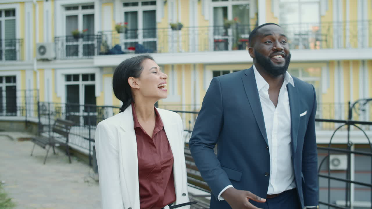 una pareja de negocios multiétnica que se ríe caminando por una calle urbana