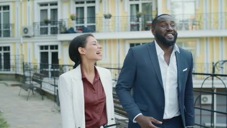 laughing multi ethnic business couple walking at urban street