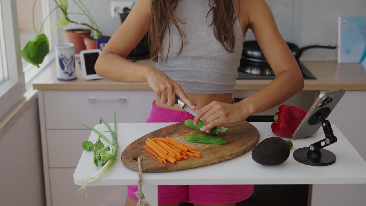 Mujer cortando verduras en la cocina para preparar una comida saludable