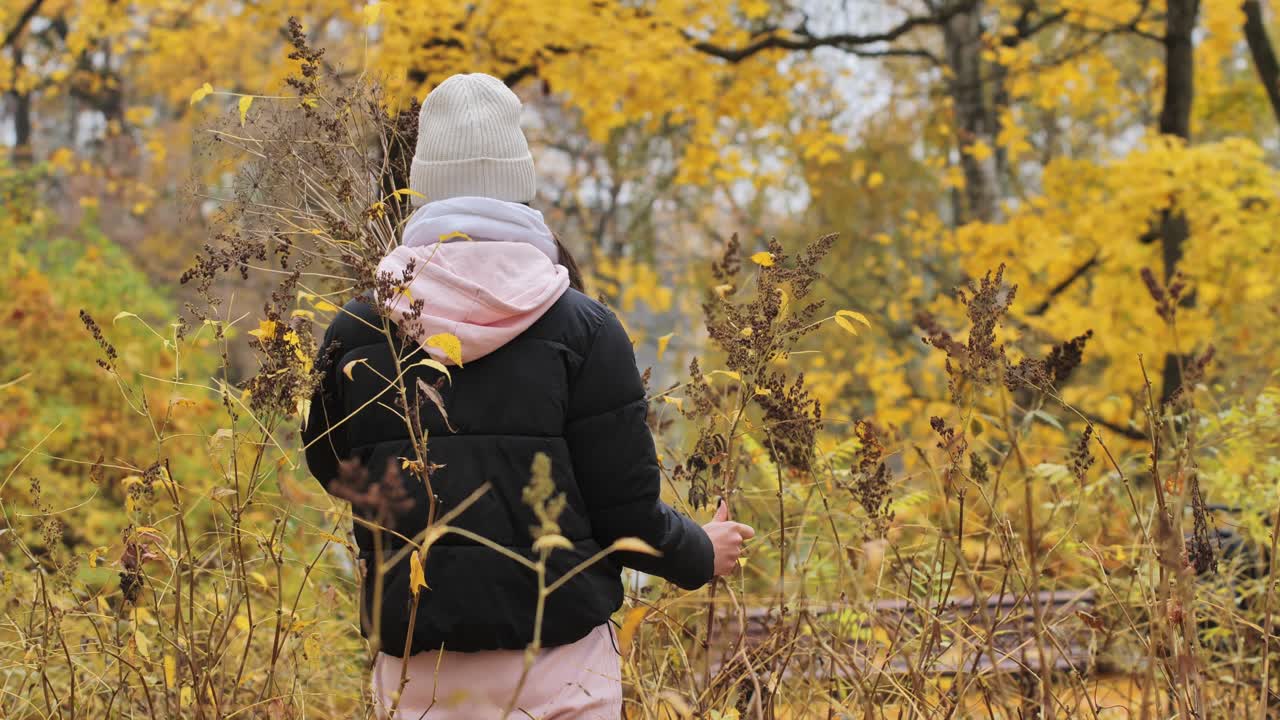 Woman surrounded by yellow leaves, interacting with nature, Serene autumn moment