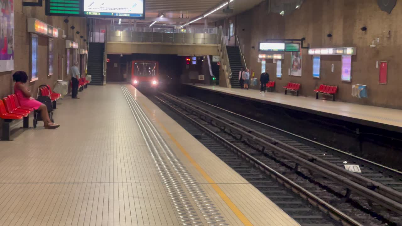 Metro train approaching a station platform with commuters
