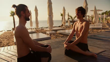 Two-guys-sit-and-meditate-on-a-sunny-beach-in-the-morning.-Harmony-of-body-and-mind
