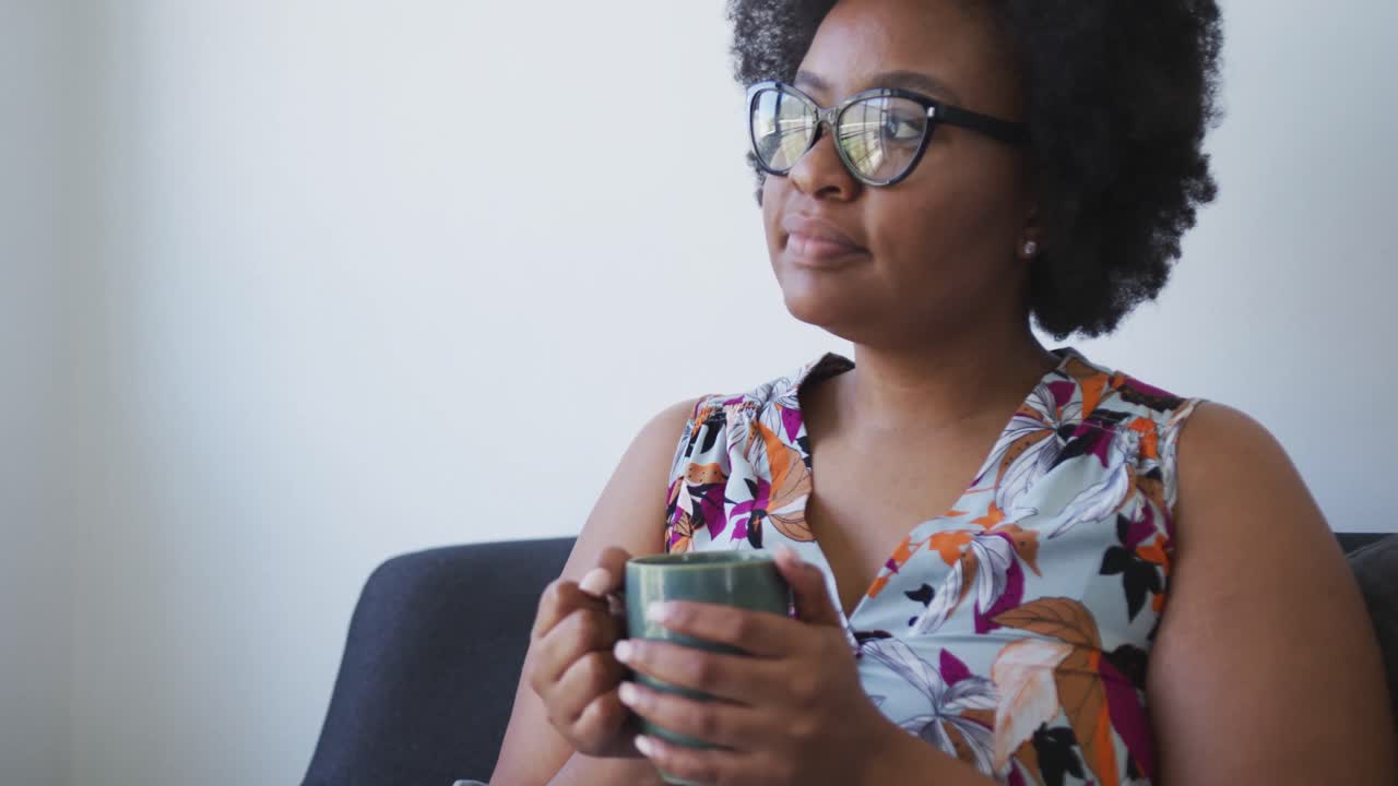 más tamaño mujer afroamericana sentada en el sofá relajándose con una taza de café