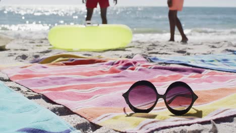 Video-of-sunglasses,-towels-and-beach-equipment-lying-on-beach
