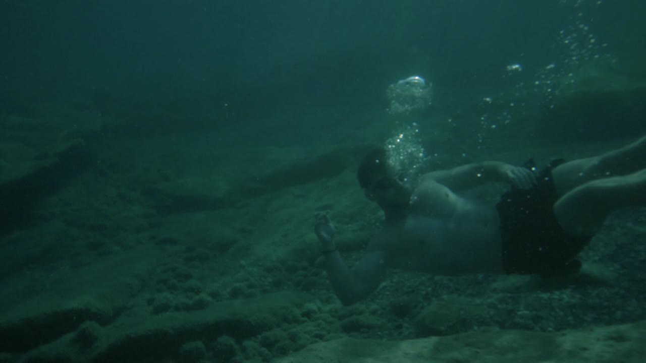 hombre atlético se sumerge bajo el agua en el mar