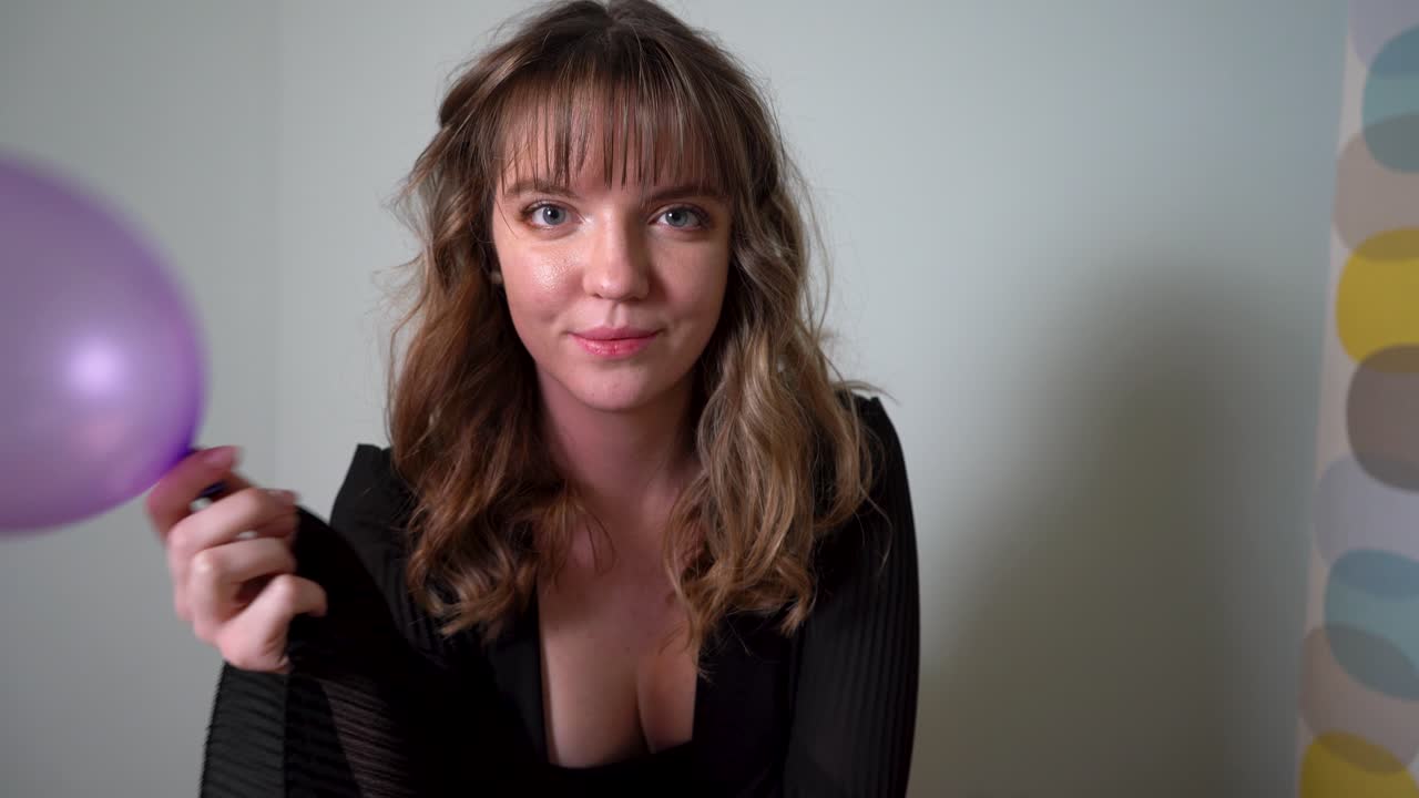 그녀의 얼굴을 덮고 풍선을 가지고 노는 젊은 여자