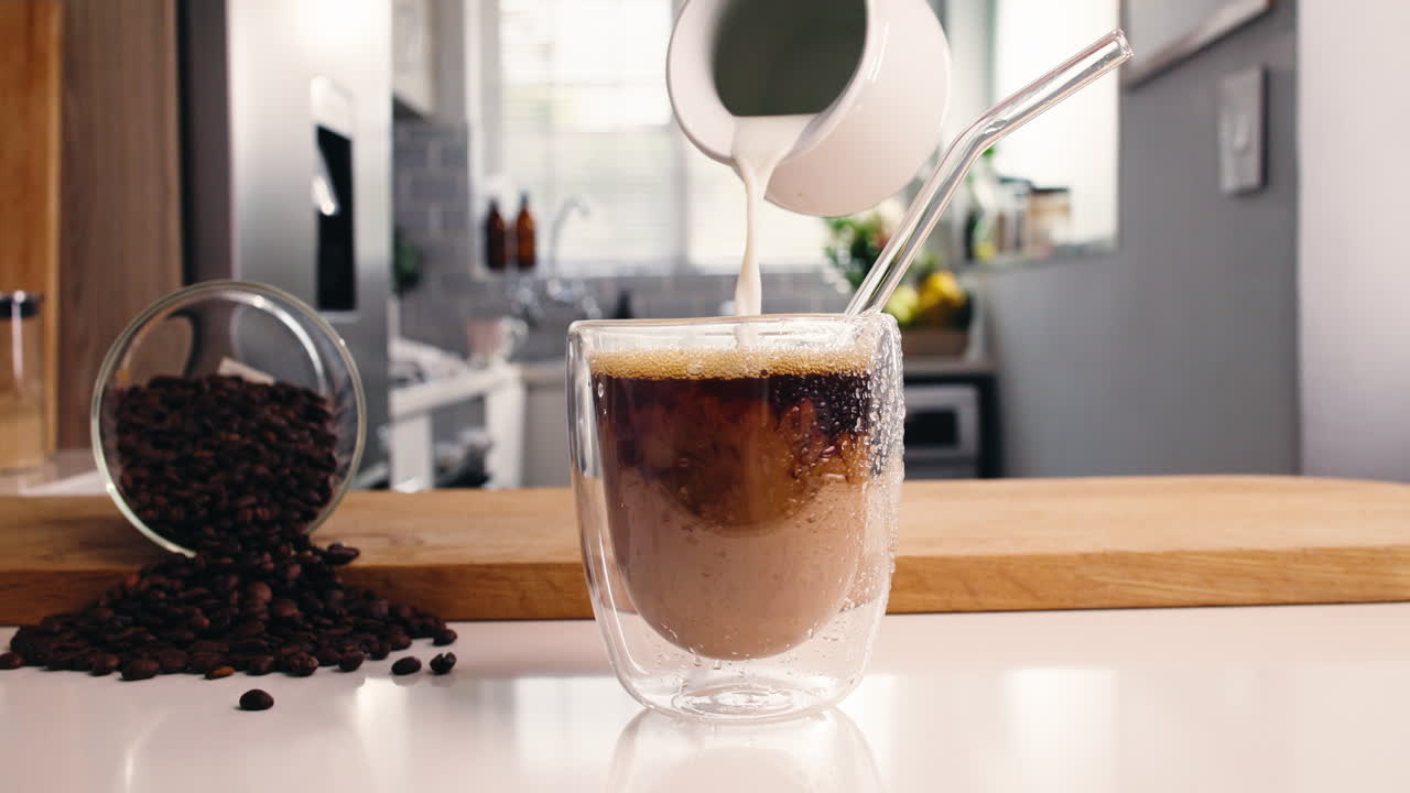 キッチンカウンターにコーヒー豆を添えて、アイスコーヒーにミルクを注ぐ