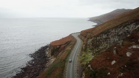 car driving on a mountain road next to the atlantic ocean