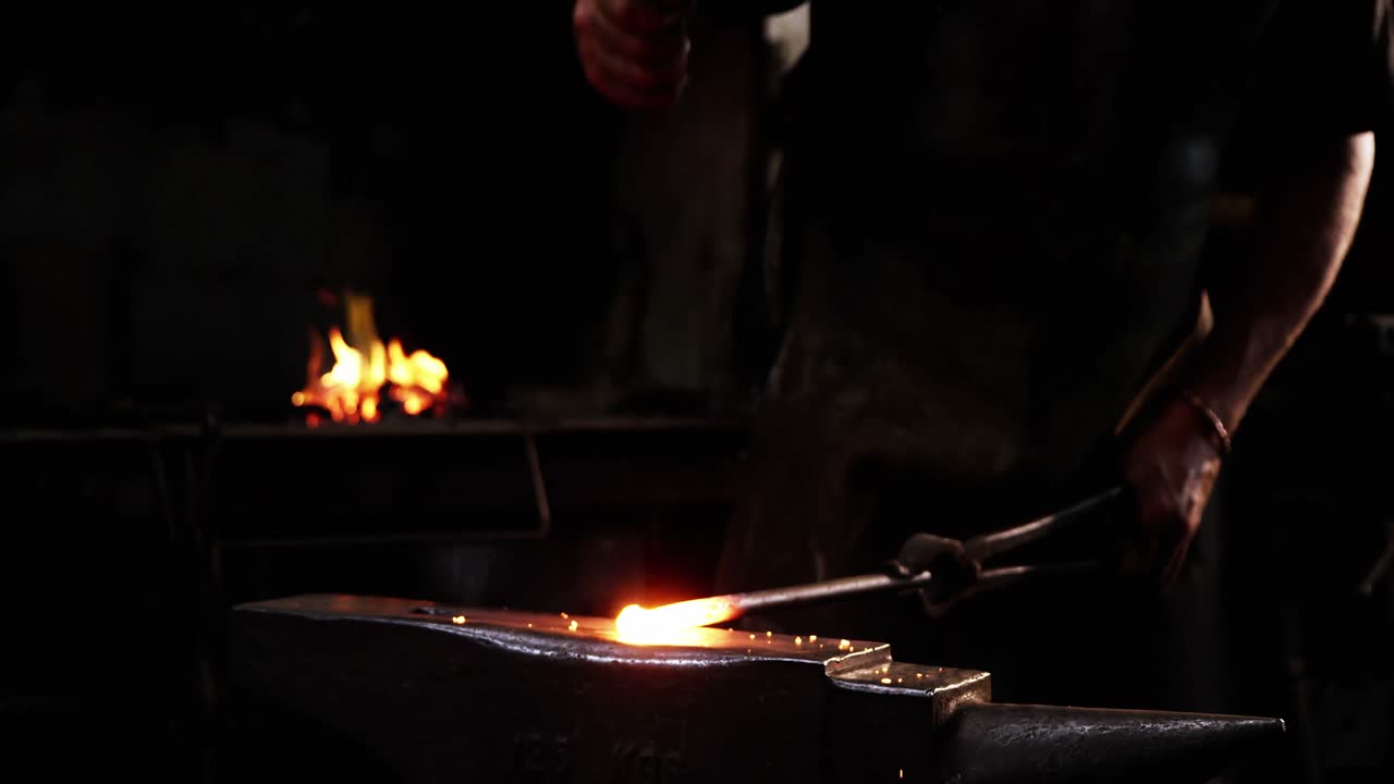 sección media de un herrero trabajando en una barra de hierro