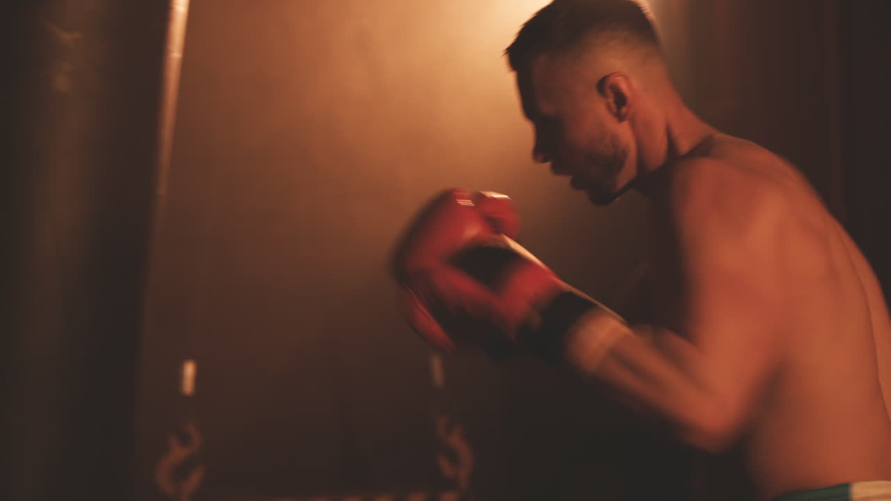 펀칭 백을 쳐서 워밍업하는 shirtless 복서 남성