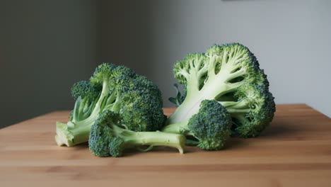 fresh and raw, slow push in to green broccoli on light wooden butcher's block