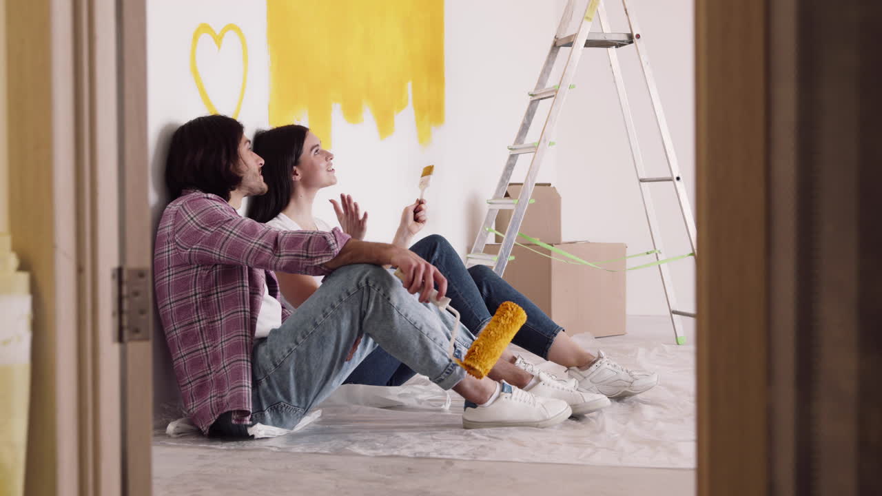 pareja pintando una pared en un nuevo hogar
