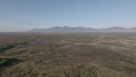 Amplias-Imágenes-Aéreas-Que-Vuelan-A-Través-Del-Desierto-De-Arizona-Al-Sol-De-La-Mañana-Que-Muestran-Un-Camino-Sinuoso-Y-Montañas-En-El-Fondo