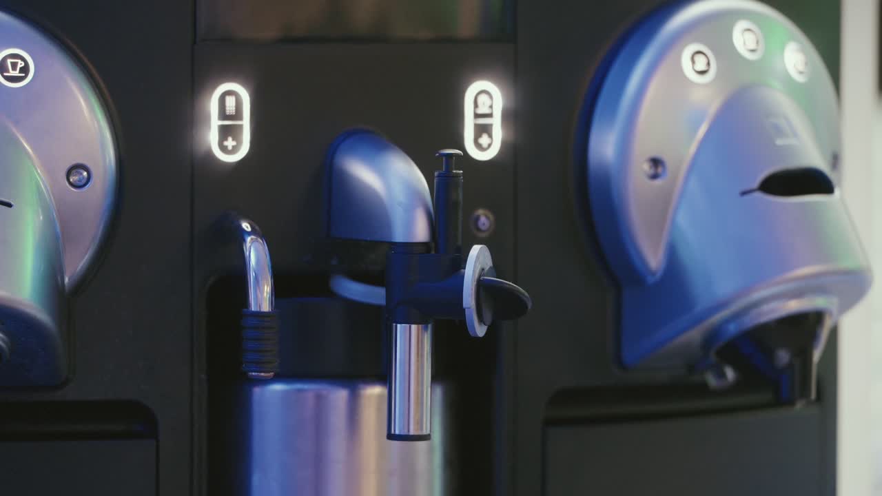 Dispensador de cafetera con boquilla de vapor y panel de control iluminado.