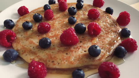 spinning pile of crepes with raspberries, blueberries and honey in celebration of french candlemas or chandeleur