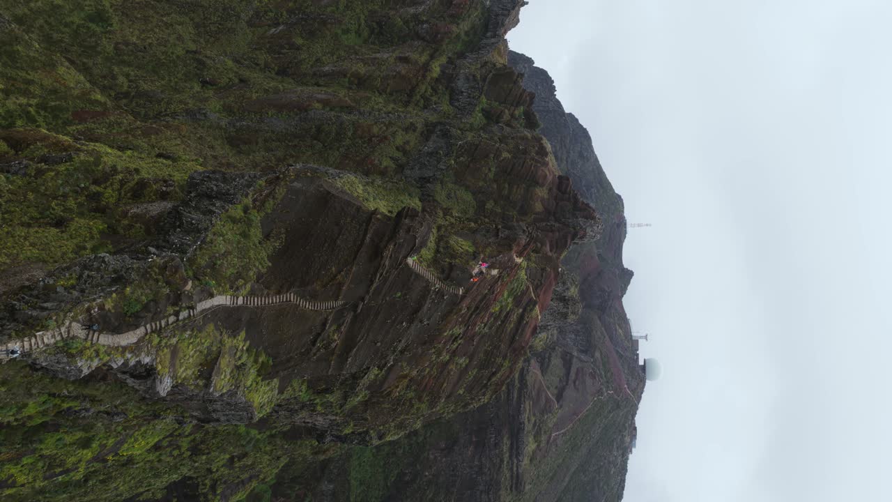 Wooden stairs climbing the mountain peak of Pico do Arieiro, Madeira island, Portugal, aerial view, vertical video