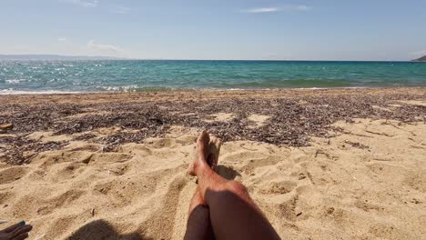 joven apuesto tomando el sol en la playa de arena