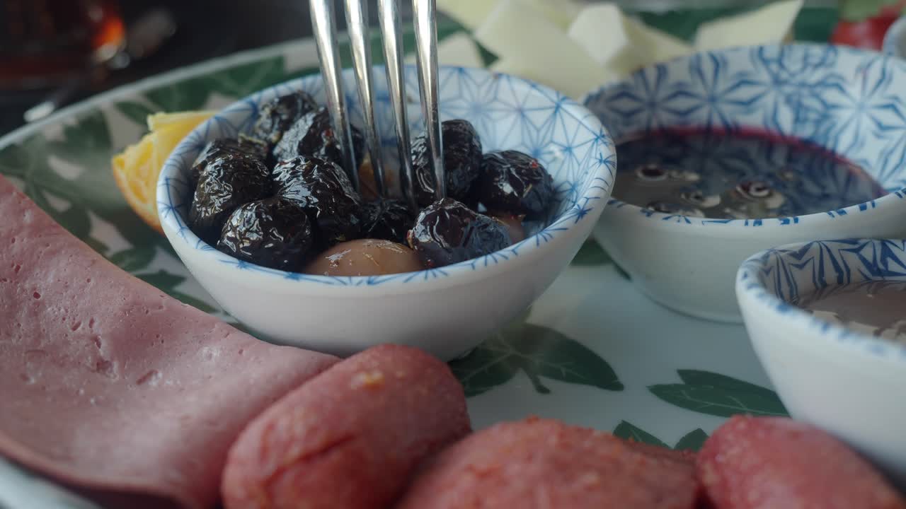 Nærbillede af en gaffel, der tager en oliven fra en morgenmadstallerken
