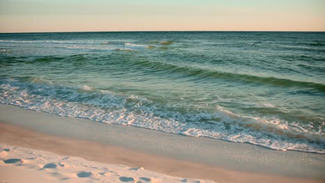 Aufnahmen-Des-Ozeans-An-Einem-Warmen,-Sonnigen-Abend-Mit-Fußspuren-Im-Sand-2