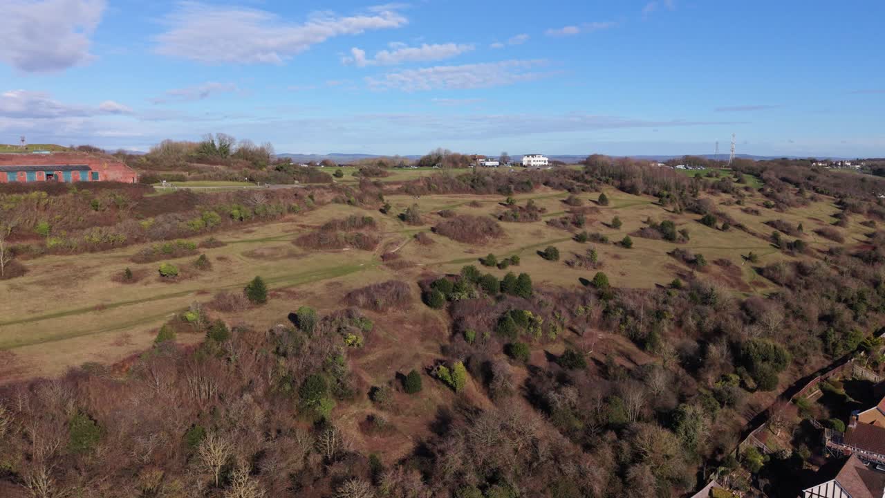 Forte Widley Portsmouth, voo sobre Swanick e colina passando pelo forte militar reaproveitado e sua posição acima de Portsmouth, olhando para o interior sobre a paisagem ondulada sob sol forte.