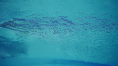 underwater slow motion scene with sunlight casting patterns on wave pool bottom