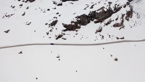 Following-a-car-at-mountain-crossing-in-Norway---Snowy-landscape---grey-cloudy-day