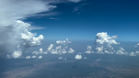 pov fpv flying through a sky with a storm cloud on the left hand side an some cottony clouds ahead in a blue sky