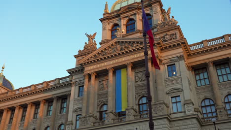 ukrainian flag on facade of prague national museum, czech flag on pole