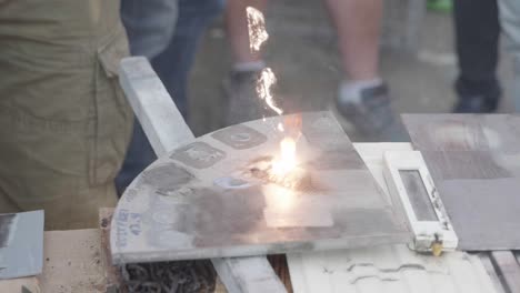 group-of-man-showcasing-laser-cleaning-device,-burning-dirt-off-metal-surface-with-visible-beam-and-flames