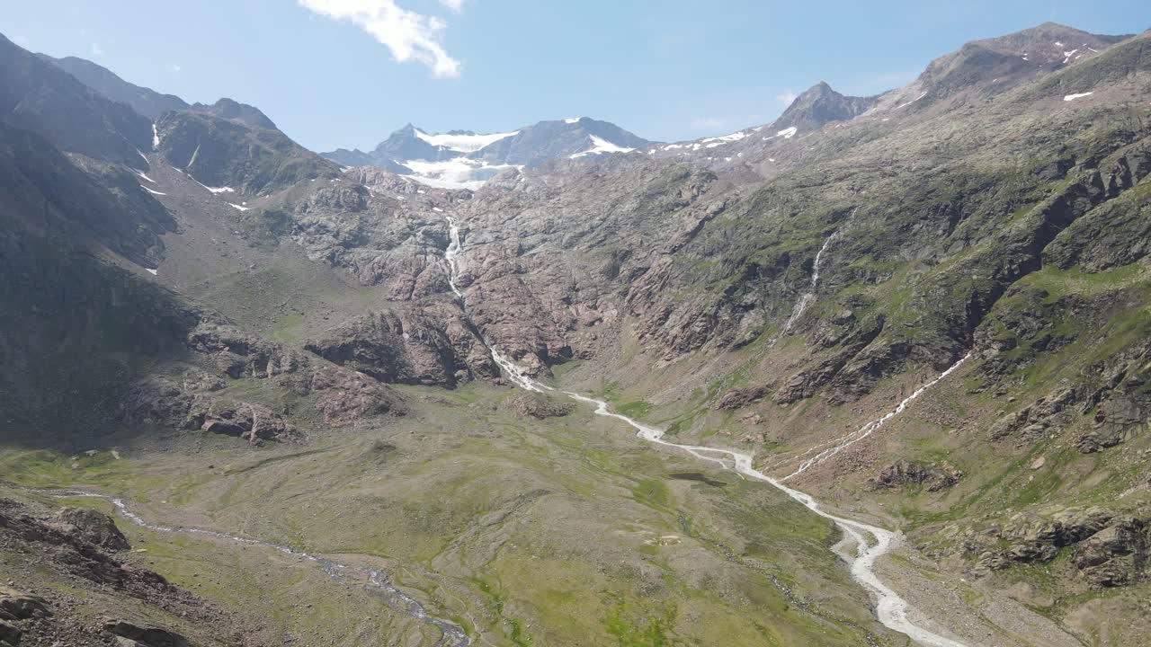wide angle drone video of the beautiful mountains in northern Italy with a giant waterfall and river. near the dolomites in South Tyrol.